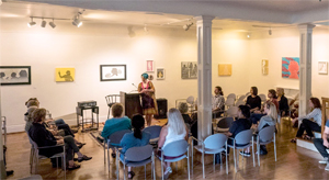 exhibition of artwork with an audience looking on during an artist's talk